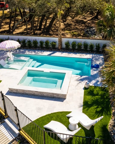 Backyard pool with spa, striped umbrella, white concrete deck, palm trees, and fenced deck area